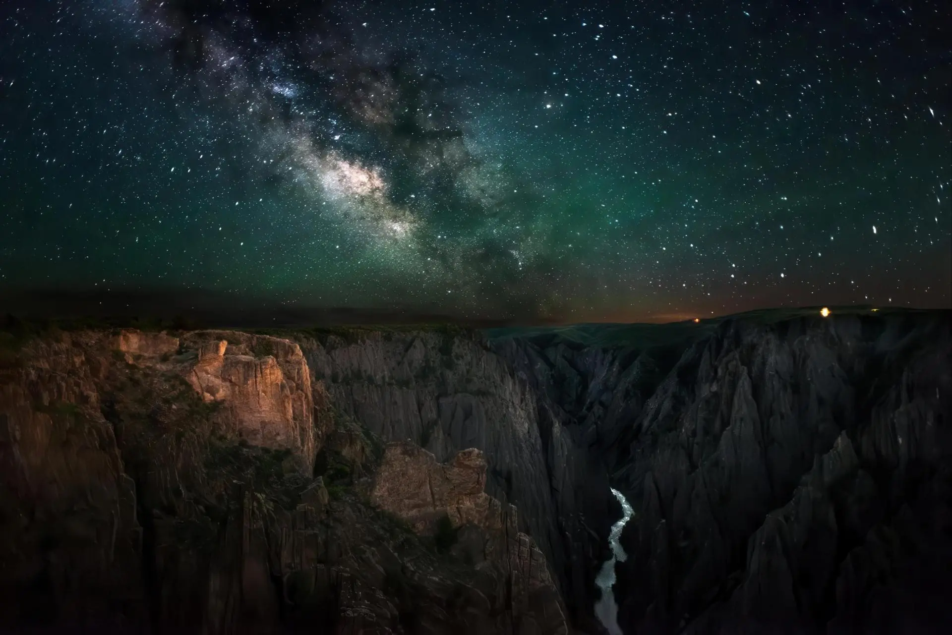 A starry sky above a canyon and winding river.